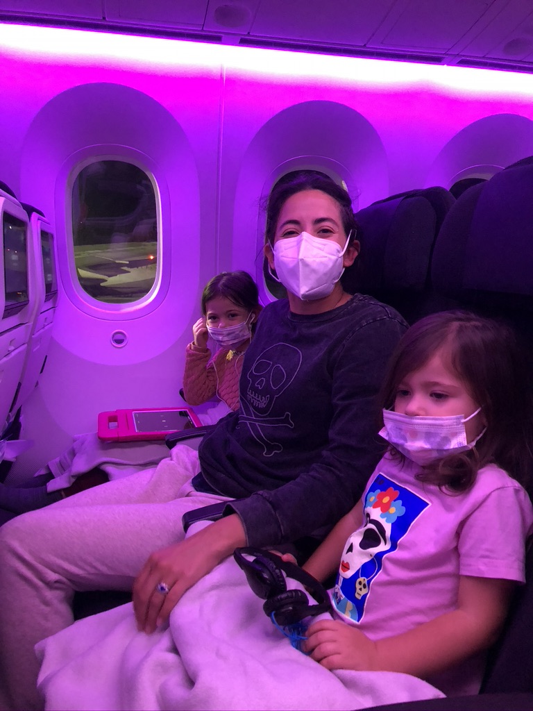 Traveling with kids during the pandemic. Two children and one adult sitting inside an airplane. Wearing masks and waiting for the plane to take off.