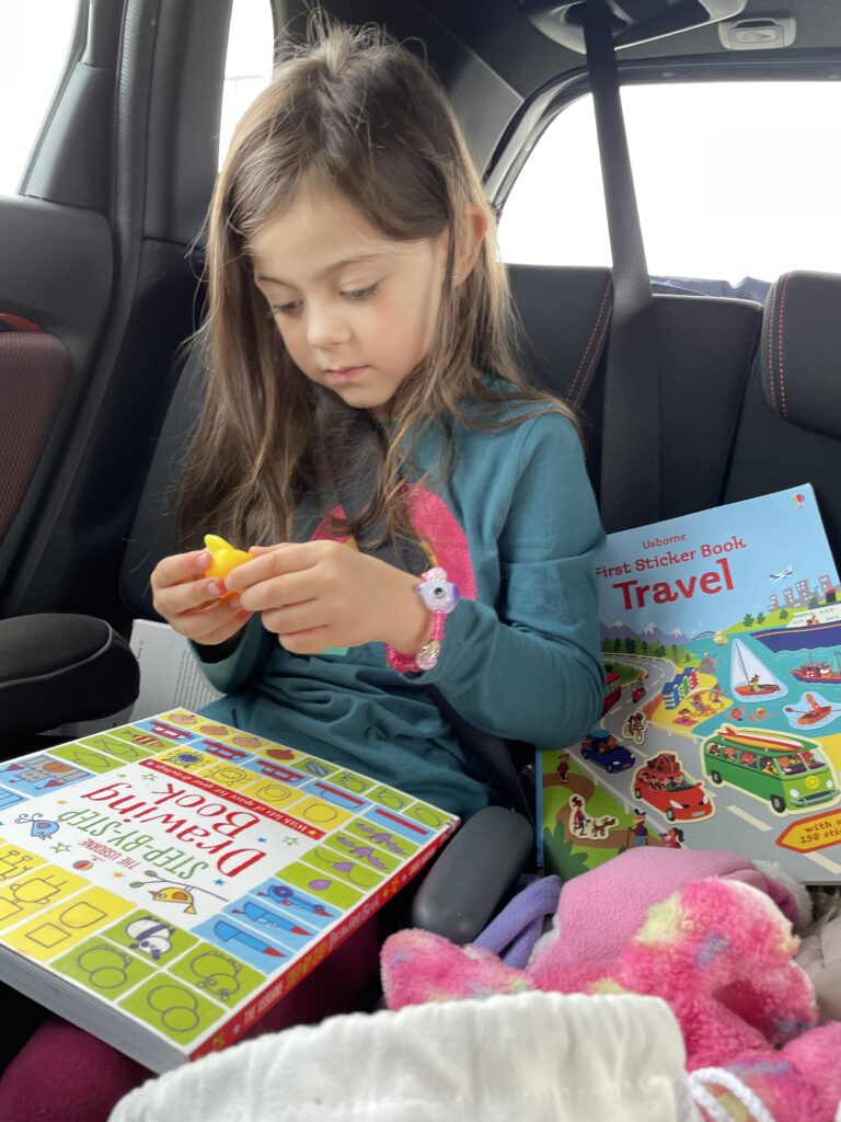 little girl playing with kids entertainment travel kit in car seat