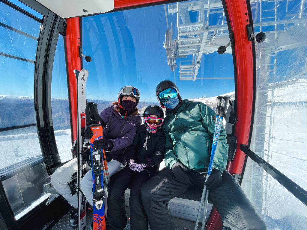 family wearing ski gear sitting inside gondola at the cardrona ski field 
