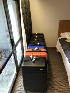 Suitcases lined up neat and tidy in managed isolation quarantine hotel room. 