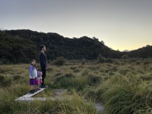 male and two small girls staring at the sunset on wetlands walk at Awaroa lodge