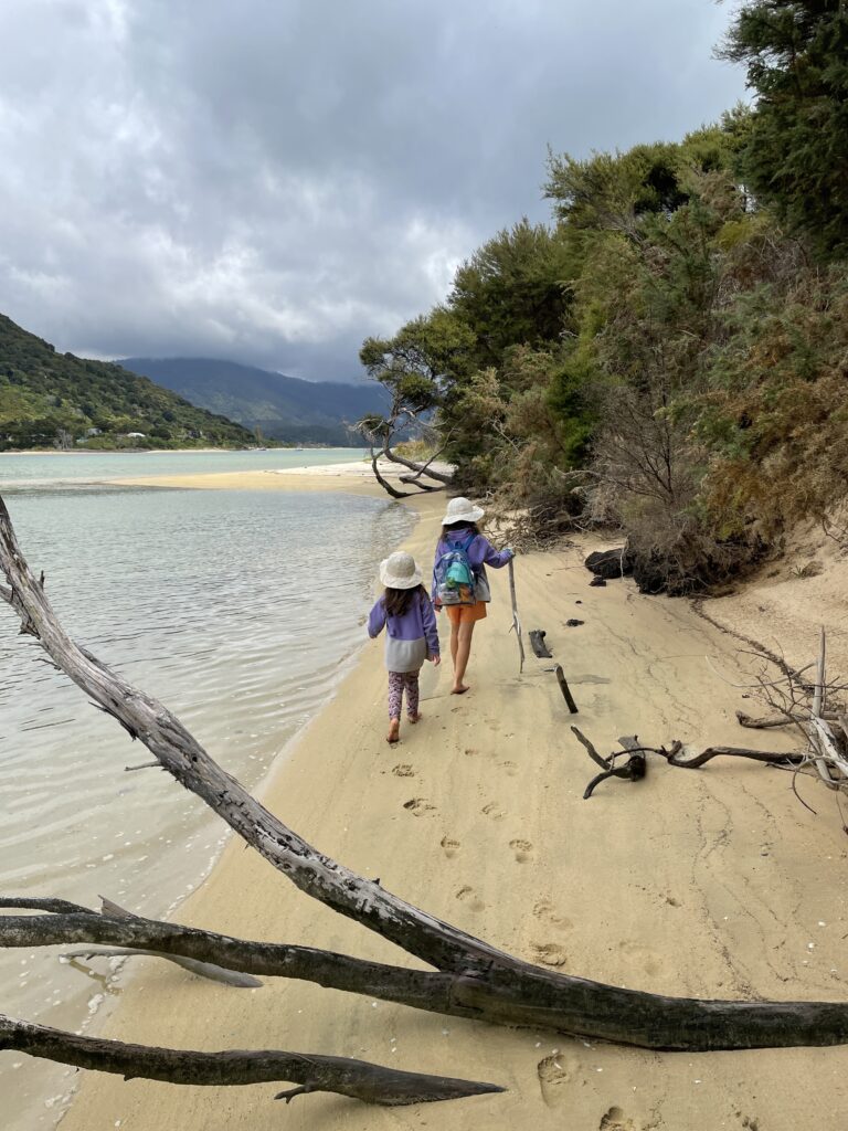 two small girls walking ahead during Abel Tasman hike by the beach