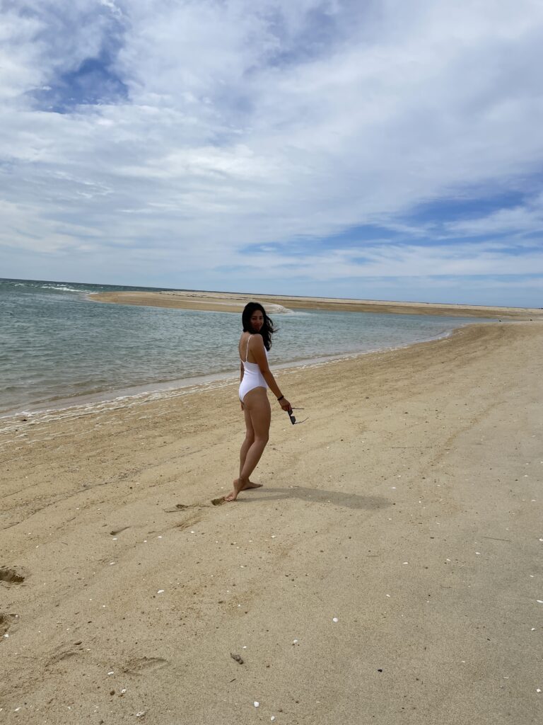 woman in bathing suit walking away at Awaroa Bay beach