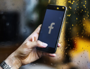 hand holding phone with Facebook logo on the screen