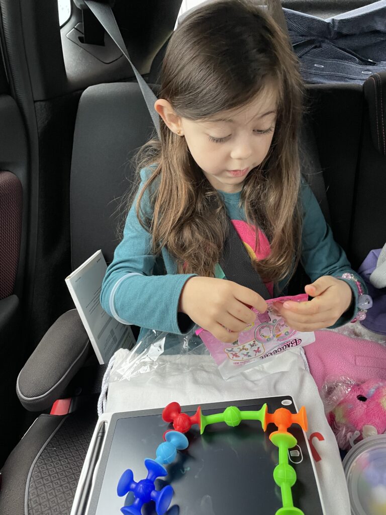 little girl playing with kids travel kit in car seat