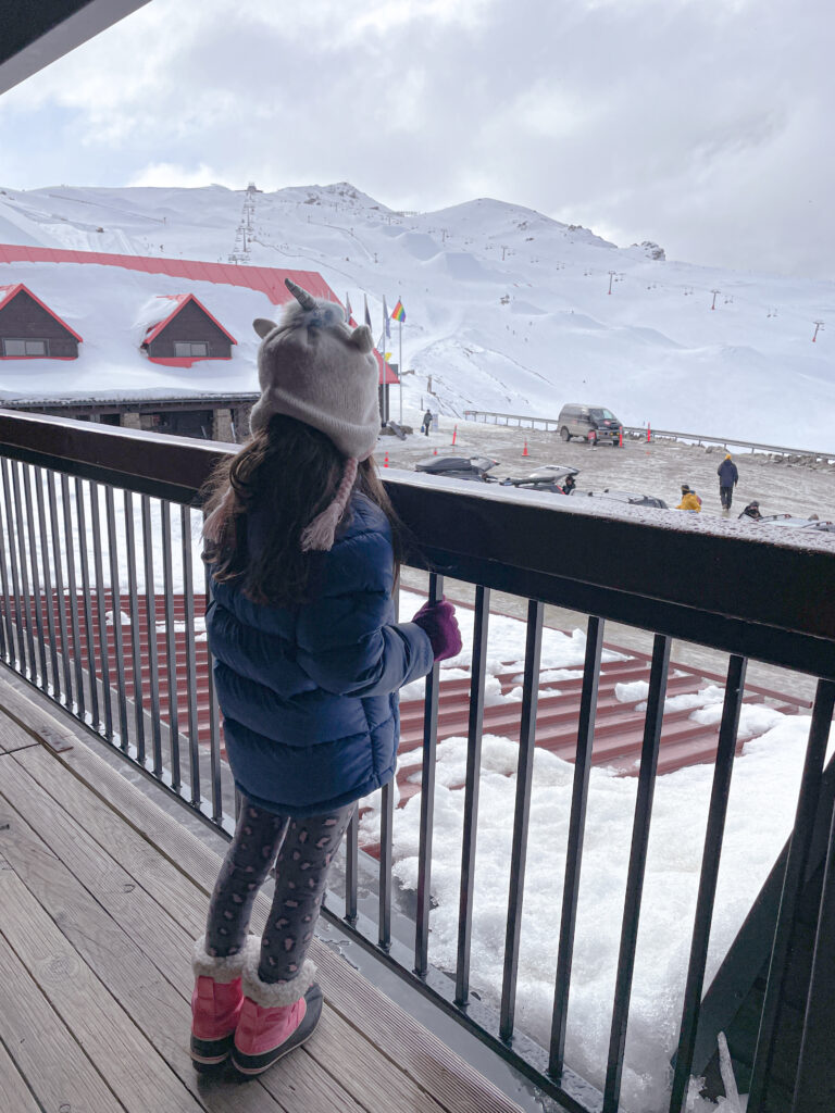 little girl looking out from apartment walkway at the Cardrona New Zealand ski resort