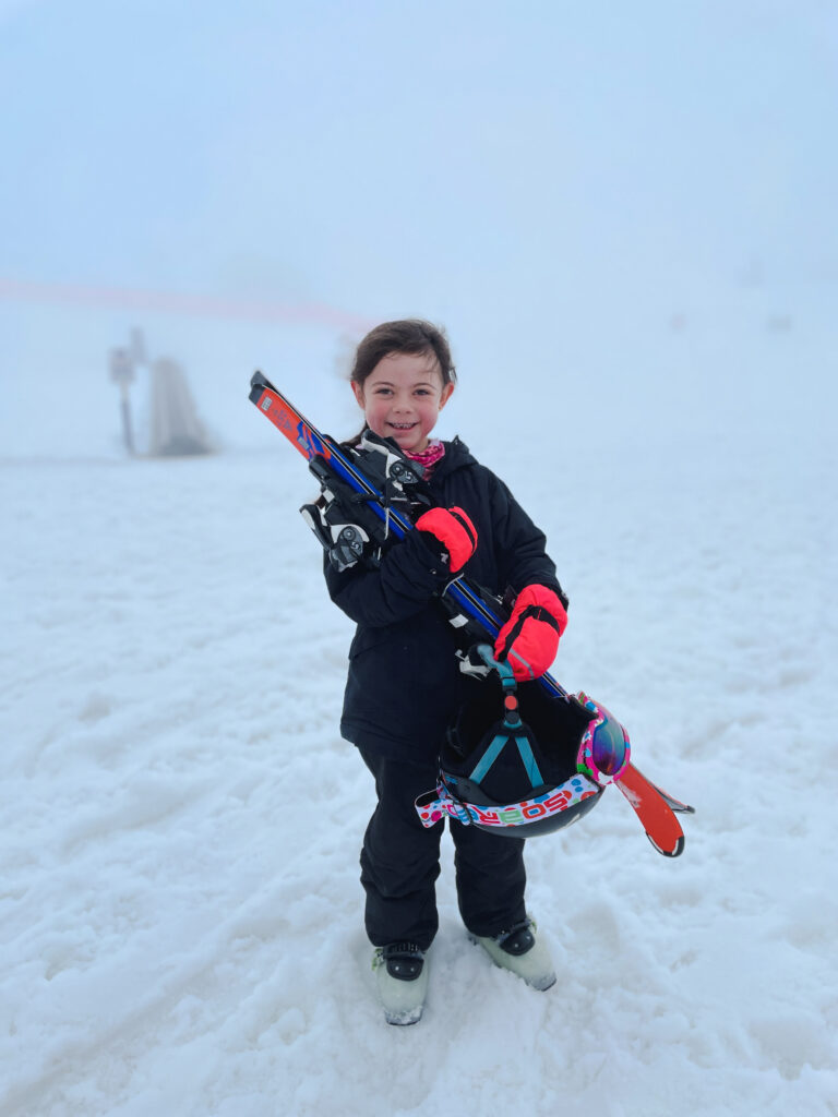 little girl in ski gear standing after finishing youth lessons at a New Zealand ski resort